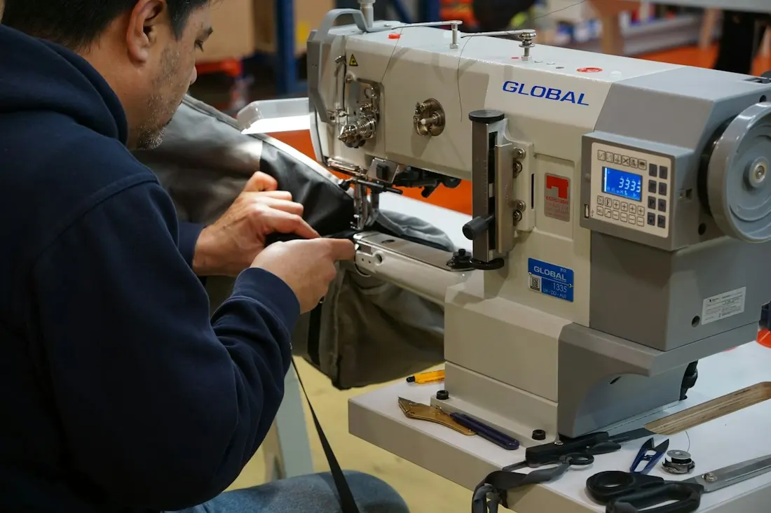 Hands finishing a garment seam inside the Sévigné atelier